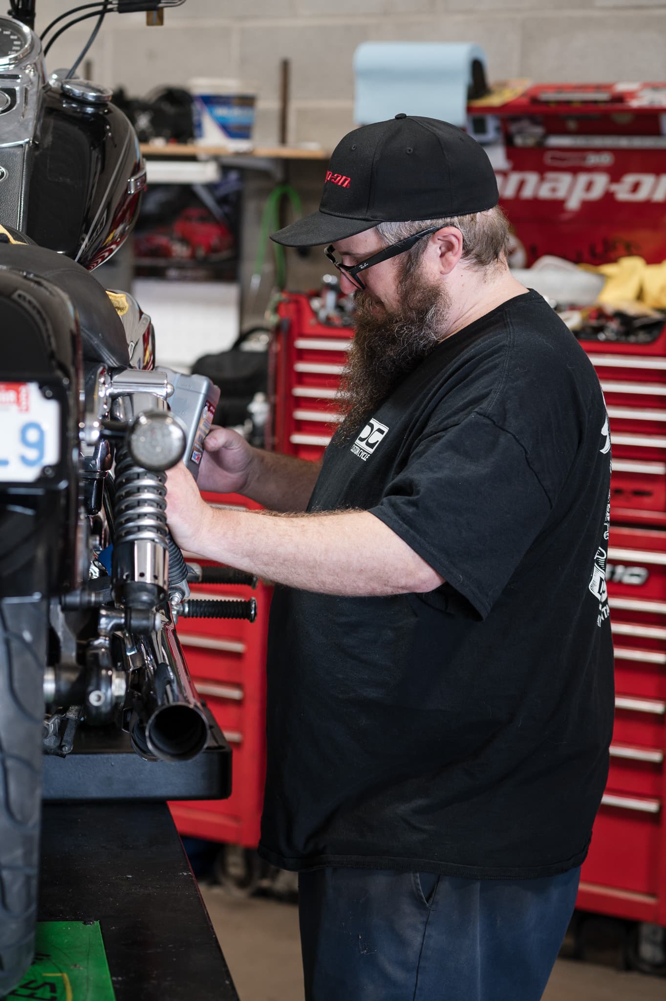 Tech using an impact gun on the rear shock of a Harley up on the bench